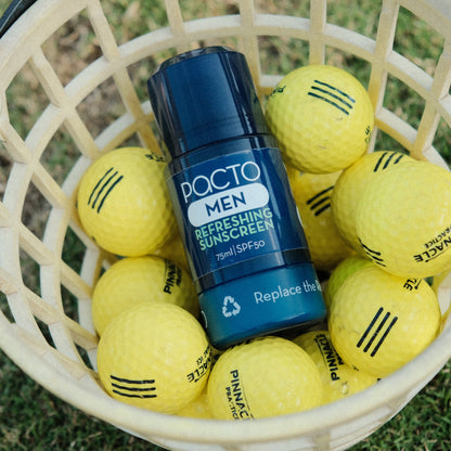 Pacto Men refreshing sunscreen bottle among golf balls in a basket on grass