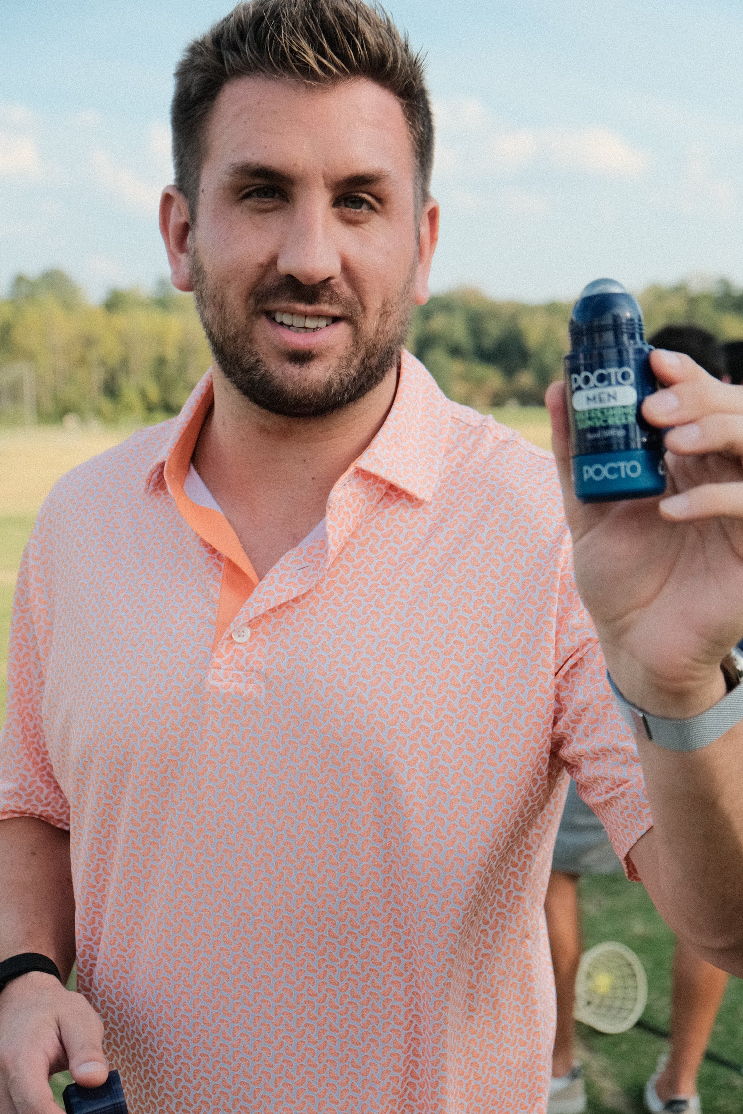 Man holding a Pacto sunscreen with a blurred outdoor background