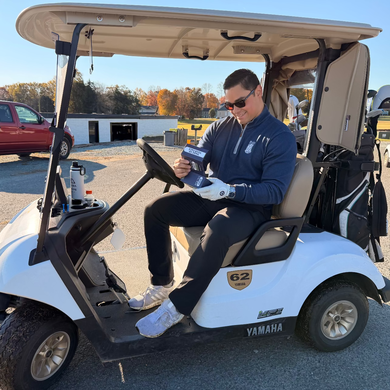 Man sitting in a white Yamaha golf cart with a clear sky background